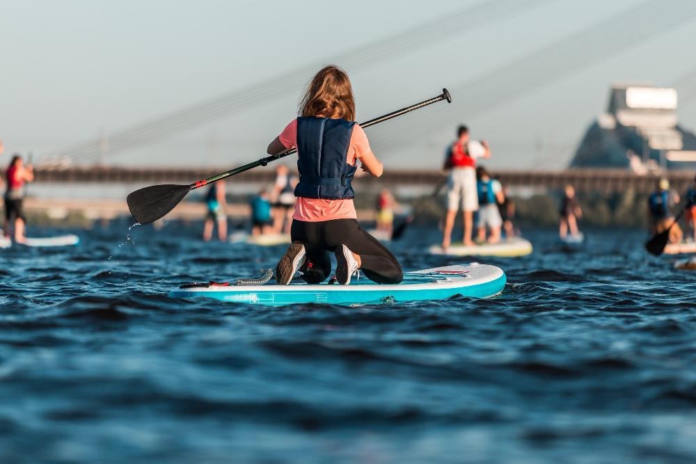 Group paddleboarding on open water under cloudy sky.