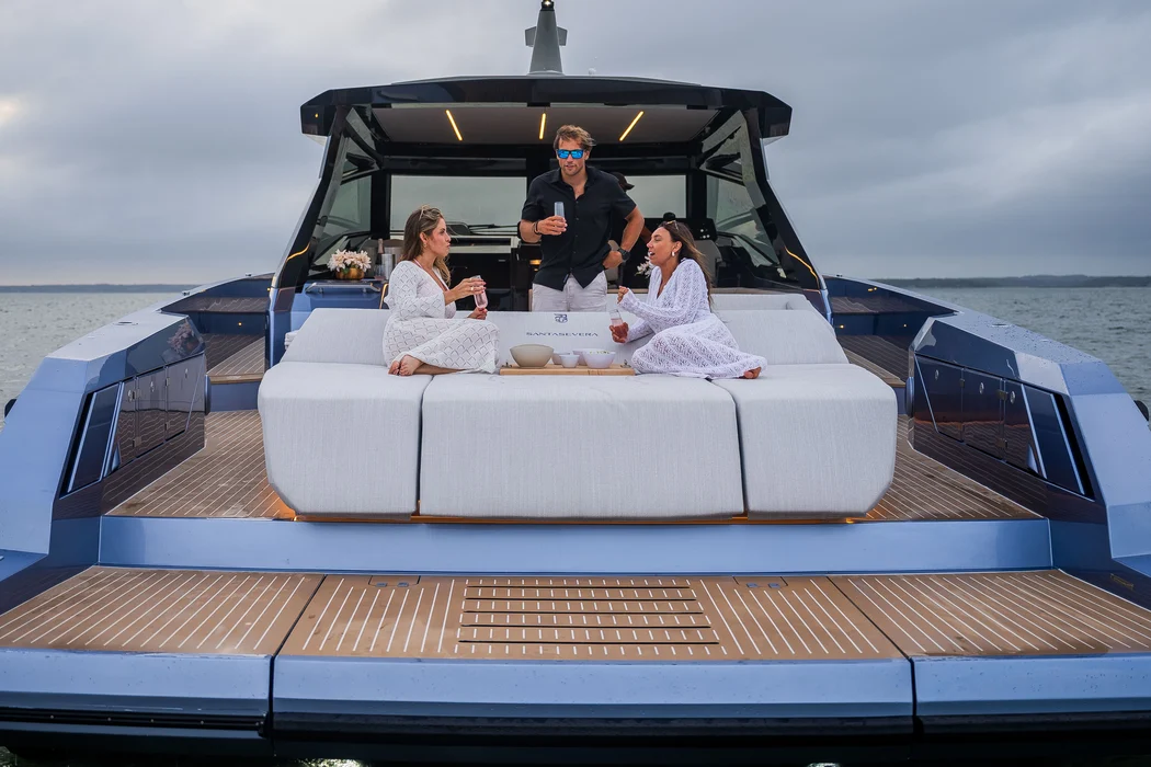 Corporate guests relaxing on branded luxury yacht lounge deck.