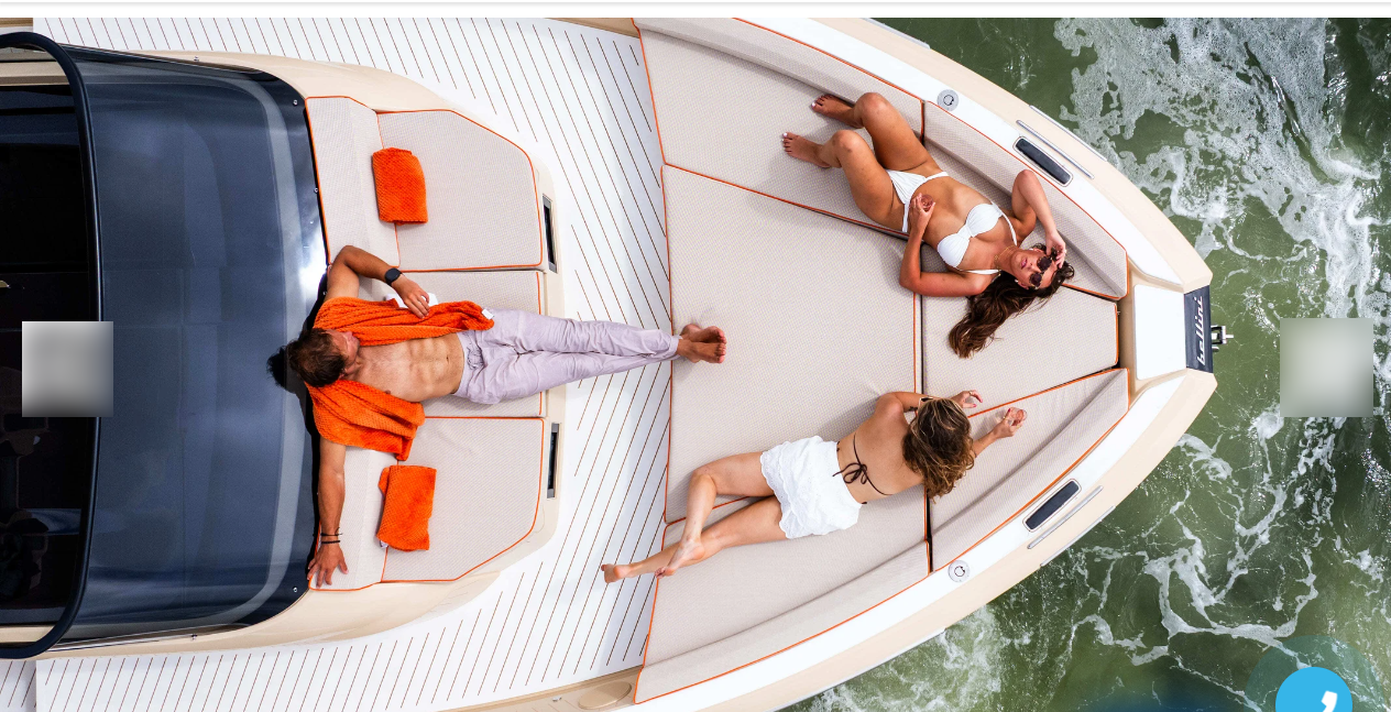 Passengers lounge on luxury yacht with orange-accented deck cushions.