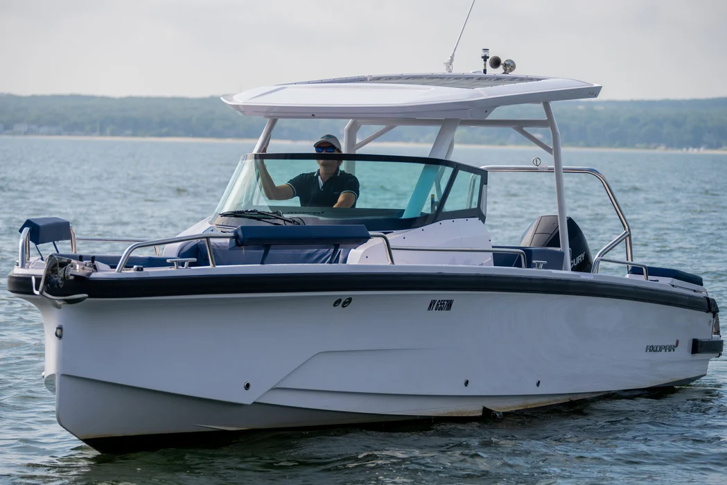 Modern rented motorboat cruising with driver near shoreline trees.