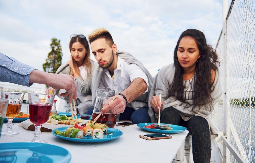 Group of people sushi on a boat.