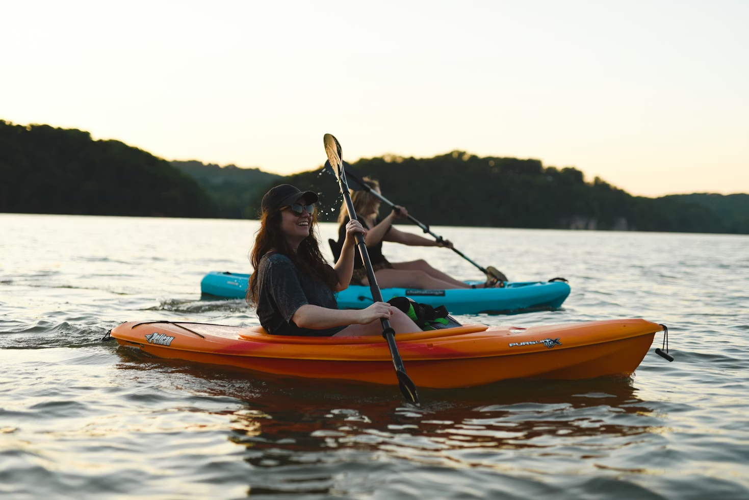 Two people kayaking with a scenic shoreline.
