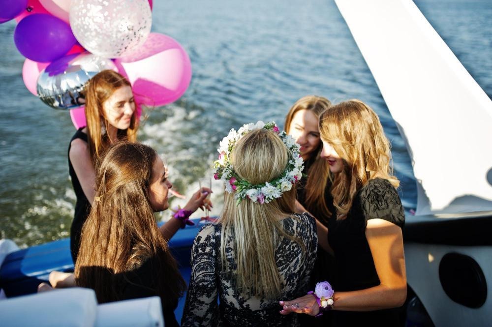 Corporate yacht party with balloons, floral crown, and water.