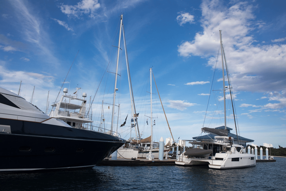 Docked yachts and sailboats under bright blue sky marina.