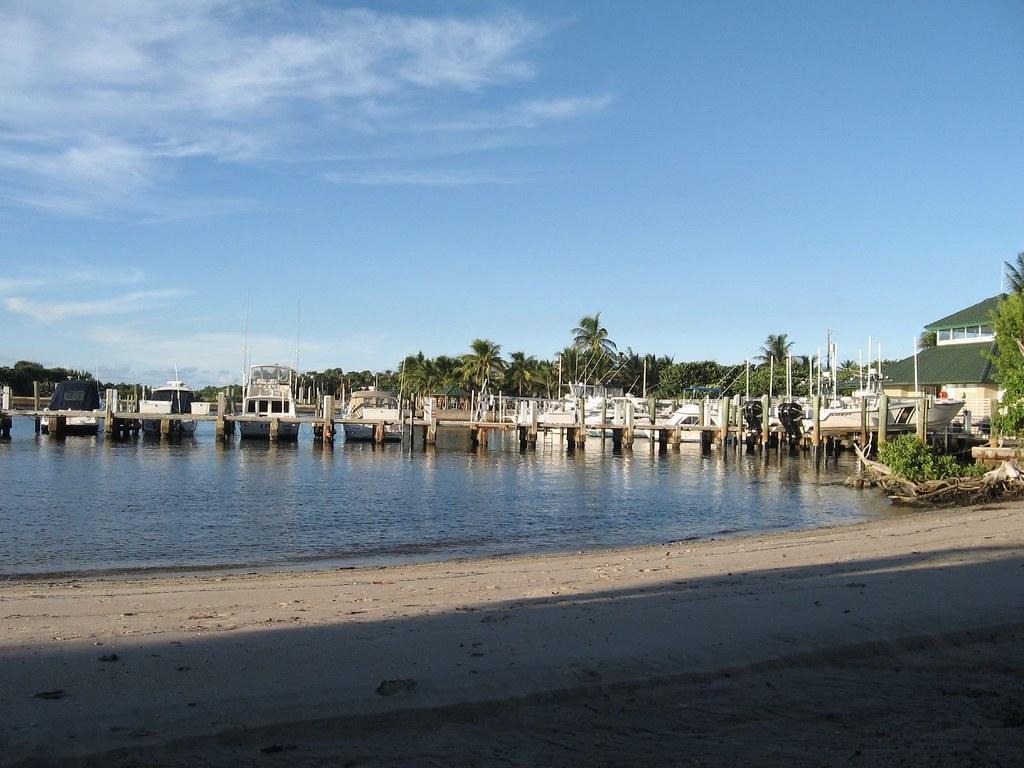 Boynton Inlet marina with boats, sandy beach, and palms.