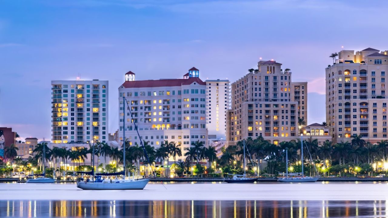Twilight West Palm Beach skyline with sailboats and palms.