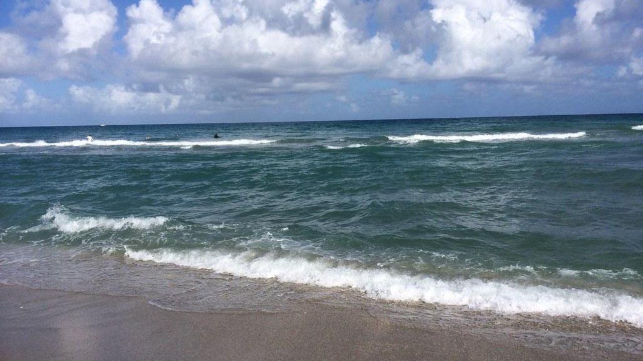  Juno Beach shoreline with rolling waves beneath towering clouds​‌ 